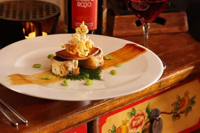 a plate with a dessert on a table with a glass of wine at Hampshire Hotel Petit Nord in Hoorn