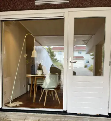 a sliding glass door leading into a dining room with a table at Studio J. in Egmond aan Zee