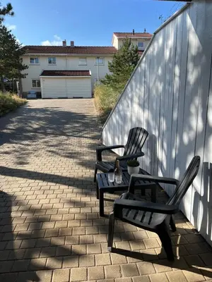 two black chairs sitting on a sidewalk next to a fence at Studio J. in Egmond aan Zee