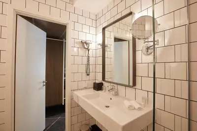 a white bathroom with a sink and a mirror at Carlton President in Utrecht