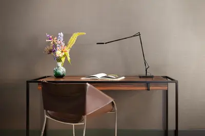 a desk with a vase of flowers and a lamp at NH Collection Amsterdam Flower Market in Amsterdam
