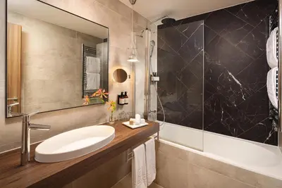 a bathroom with a sink and a tub and a mirror at NH Collection Amsterdam Flower Market in Amsterdam