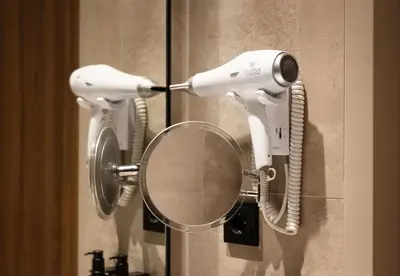 a hair dryer hanging on a wall with a mirror at NH Collection Amsterdam Flower Market in Amsterdam