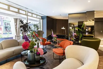 a waiting room with couches and orange chairs at NH Collection Amsterdam Flower Market in Amsterdam