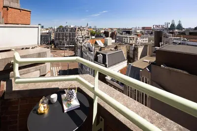 a table on a balcony with a view of a city at NH Collection Amsterdam Flower Market in Amsterdam