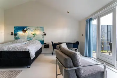 a bedroom with a bed and a chair and a window at Huize Leeghwater in Zuidoostbeemster