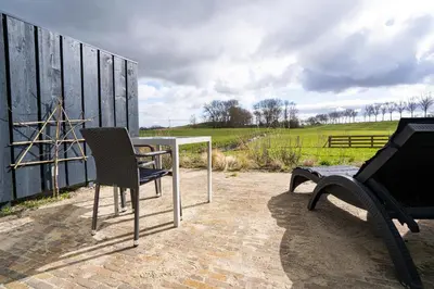a patio with two chairs and a grill at Huize Leeghwater in Zuidoostbeemster