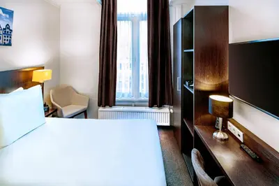 a hotel room with a bed and a flat screen tv at Hotel Nes Amsterdam in Amsterdam