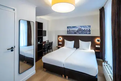 a hotel room with a bed and a desk at Hotel Nes Amsterdam in Amsterdam