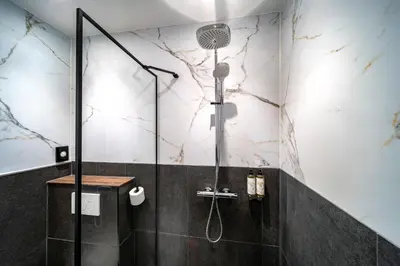 a shower in a bathroom with black and white marble at Hotel Nes Amsterdam in Amsterdam