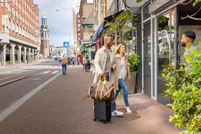 a man and woman walking down a street with a suitcase at Boutique Hotel Albus Amsterdam Centre in Amsterdam