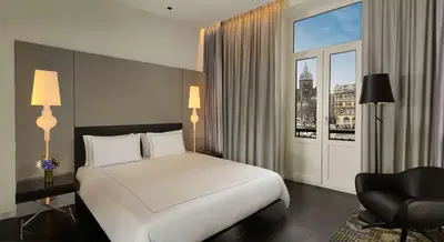 a bedroom with a bed and a chair and a window at Park Plaza Victoria Amsterdam in Amsterdam