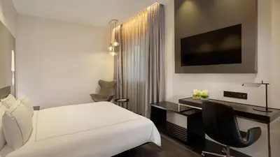 a bedroom with a bed and a desk and a tv at Park Plaza Victoria Amsterdam in Amsterdam