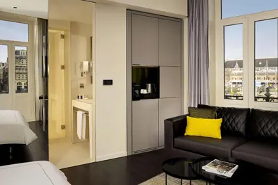 a living room with a black couch and a yellow pillow at Park Plaza Victoria Amsterdam in Amsterdam