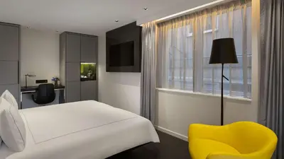 a bedroom with a white bed and a yellow chair at Park Plaza Victoria Amsterdam in Amsterdam