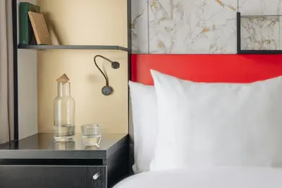 a bed with a bottle and a glass on a night stand at Leonardo Boutique Hotel The Lancaster Amsterdam in Amsterdam
