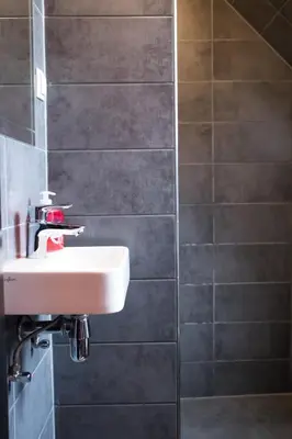 a bathroom with a white sink and a shower at Amsterdam Hostel Uptown in Amsterdam