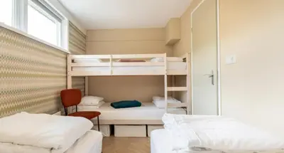 a room with two bunk beds and a window at VT wonen stijl vakantiebungalow nabij zee, strand, bos en duinen voor 6 personen in Warmenhuizen