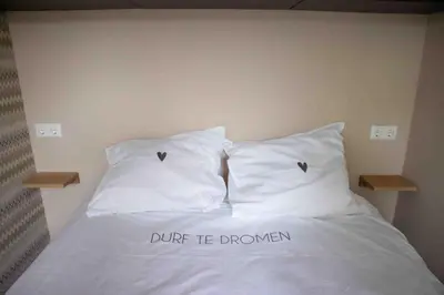 a bed with two pillows with the words dump be drown at VT wonen stijl vakantiebungalow nabij zee, strand, bos en duinen voor 6 personen in Warmenhuizen