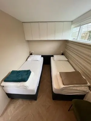 two beds in a small room with a window at VT wonen stijl vakantiebungalow nabij zee, strand, bos en duinen voor 6 personen in Warmenhuizen