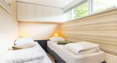 two beds in a small room with white towels at VT wonen stijl vakantiebungalow nabij zee, strand, bos en duinen voor 6 personen in Warmenhuizen