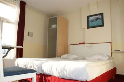 a hotel room with two beds and a chair at Hotel de Westertoren in Amsterdam
