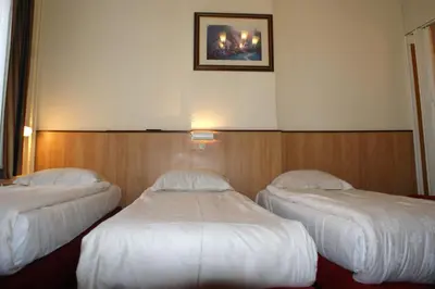 two beds in a hotel room with white sheets at Hotel de Westertoren in Amsterdam