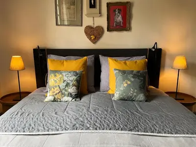 a bedroom with a large bed with two lamps at B&B De Kamer Hiernaast in Gouda