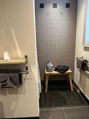 a bathroom with a bench and a shower at B&B De Kamer Hiernaast in Gouda