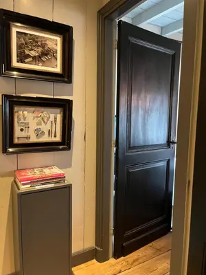 a black door in a room with paintings on the wall at B&B De Kamer Hiernaast in Gouda