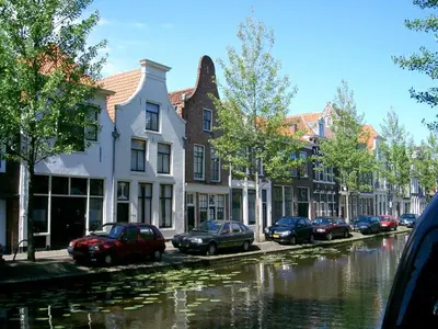 a group of cars parked on a street next to a canal at B&B De Kamer Hiernaast in Gouda