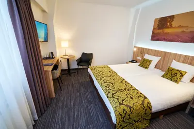 a hotel room with a bed and a desk at Amrâth Hotel Lapershoek Arenapark in Hilversum
