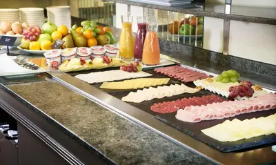 a buffet line with different types of cheese and fruit at Amrâth Hotel Lapershoek Arenapark in Hilversum