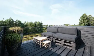 a couch and a table on a wooden deck at GreenFloat Boskoop #2 Mica & Luca in Boskoop