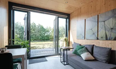 a living room with a couch and a large window at GreenFloat Boskoop #2 Mica & Luca in Boskoop