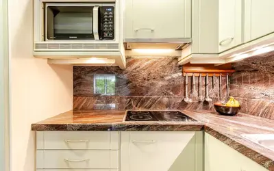 a kitchen with white cabinets and a microwave at Huisje Marie Loosdrecht in Loosdrecht