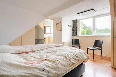 a bedroom with a bed and two chairs and a window at Huisje Marie Loosdrecht in Loosdrecht