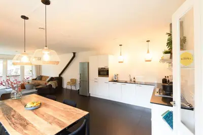 a kitchen and living room with white cabinets and a table at Spacious and attractive family home near Amsterdam in Overveen