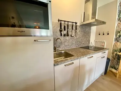 a kitchen with a stainless steel refrigerator and a sink at Glücklich am Meer Apartment Deluxe mit Wellnesszugang in Egmond aan Zee