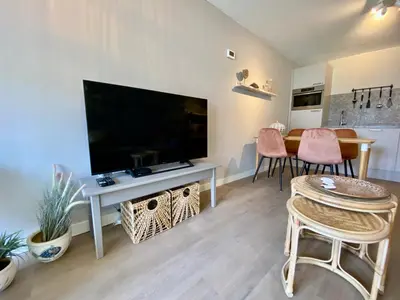 a living room with a television and a table with chairs at Glücklich am Meer Apartment Deluxe mit Wellnesszugang in Egmond aan Zee