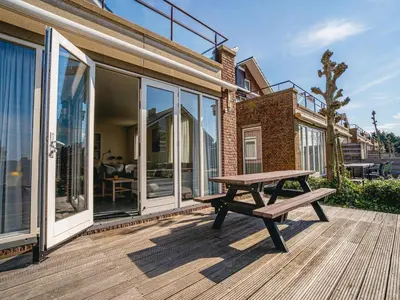a wooden deck with a bench on top of a house at Waterside Escape with Easy Access in Uitgeest