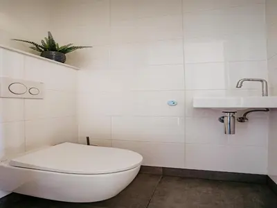 a white bathroom with a toilet and a sink at Waterside Escape with Easy Access in Uitgeest