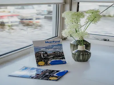 a book and a vase on a table with a window at Waterside Escape with Easy Access in Uitgeest
