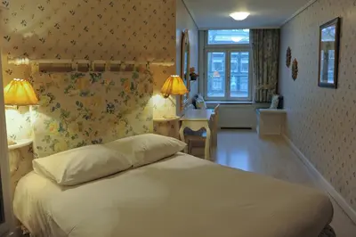 a bedroom with a bed and two lamps on the wall at Imperial Hotel Amsterdam in Amsterdam