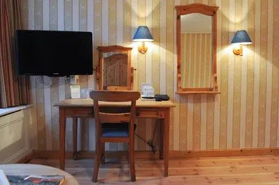 a desk with a television and a chair in a room at Imperial Hotel Amsterdam in Amsterdam