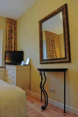 a bedroom with a mirror and a table with a television at Imperial Hotel Amsterdam in Amsterdam