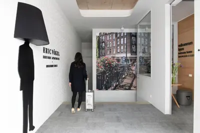 a woman standing in a hallway looking at a poster at Eric Vökel Boutique Apartments - Riverfront Suites in Amsterdam