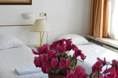 a bedroom with a bed with a vase of pink flowers at Hotel de Munck in Amsterdam