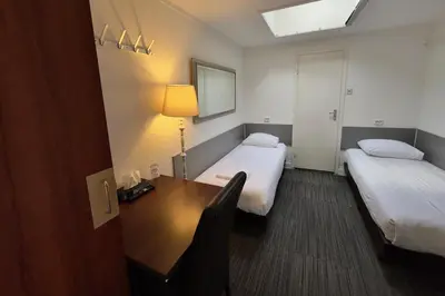 a room with two beds and a desk with a lamp at Hotel de Munck in Amsterdam