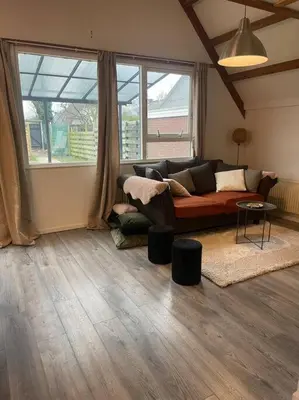 a living room with a couch and a large window at Leuke bungalow in Noord-Holland in Opmeer
